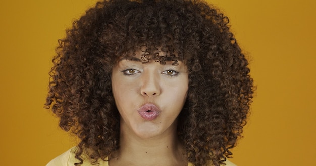 Schönes Brunettemodell auf Gelb. Lockige haare. Brasilianische junge Frau.