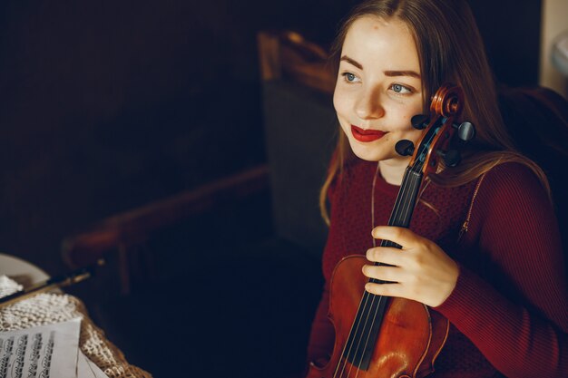 schönes elegantes Mädchen, das in einem Café mit Violine sitzt und Kaffee trinkt