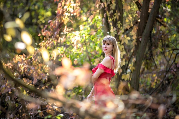 Schönes Elfenmädchen in rotem Kleid im Herbstwaldwald-Fantasiemärchen