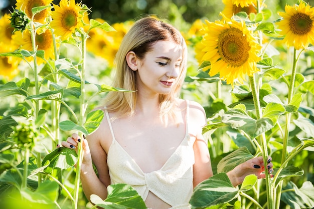 Schönes europäisches Mädchen in einem weißen Kleid auf Natur mit Sonnenblumen