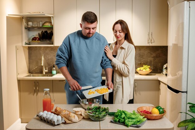 Schönes Familienpaar bereitet veganen Gemüsesalat gemeinsam in der Küche zu Gesundes Essen und Ernährungskonzept Lebensstil Zu Hause kochen