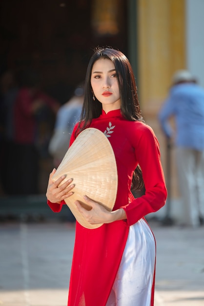 Schönes Frauenporträt des vietnamesischen Mädchens im traditionellen roten Kleid