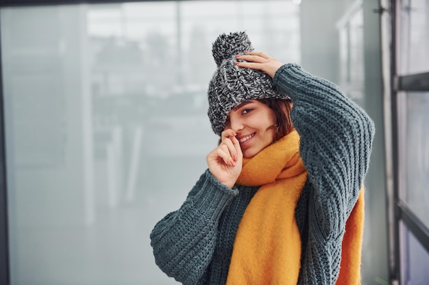 Schönes fröhliches Mädchen in gelbem Schal und in warmer Kleidung, die drinnen steht.