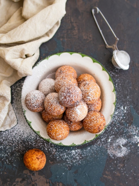 Schönes Frühstück. Hüttenkäsekrapfenbällchen mit Zuckerpulver auf einem dunklen Hintergrund. Nahansicht. Speicherplatz kopieren,