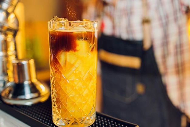 Schönes gefrorenes Cocktailglas mit Eisminze und Ananas auf einem dunklen hölzernen Barthekenbokeh-hellen Hintergrund