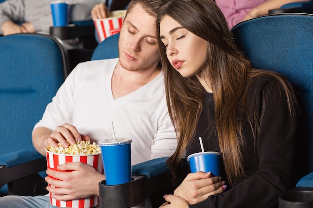 schönes gelangweiltes Paar, das während eines Films im örtlichen Kino schläft
