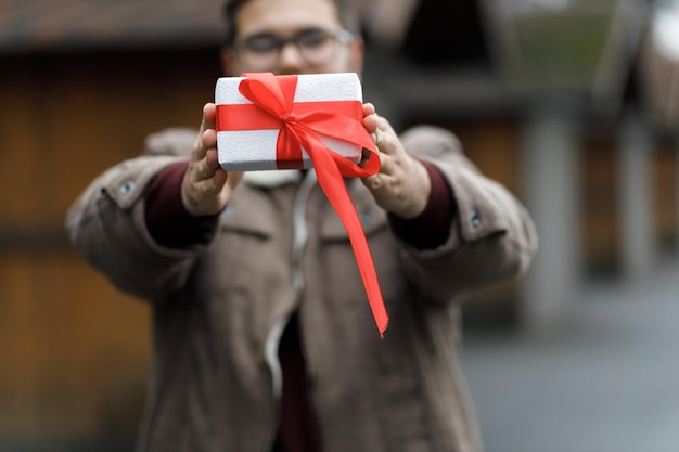 Schönes Geschenk Neujahrsdekor Der Junge hält ein Neujahrsgeschenk in seinen Händen Vorbereitung für den Urlaub Hölzerner Hintergrund KOPIERRAUM