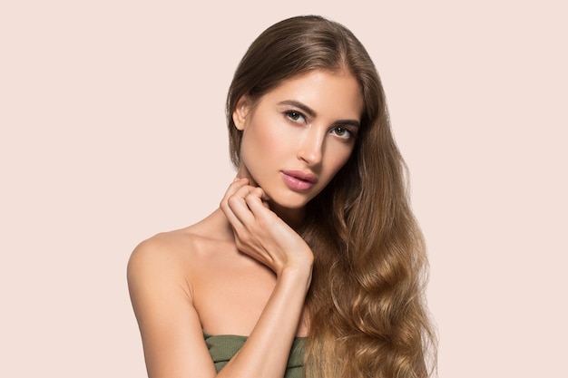 Schönes Gesicht der Frau gesund. Junges Modell der Schönheit, das sich berührt. Farbiger Hintergrund. Rosa