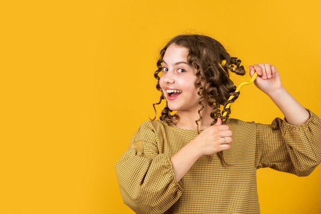 Schönes, gesundes Haar, das glänzende Locken genießt, Balsamöl-Conditioner für das Styling, Friseurbedarf, Mode und Schönheit, kleines Mädchen, Friseursalon, kleines Kind, lockiges Haar, Frisur für Party