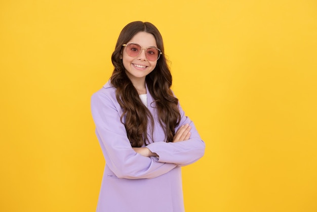 Schönes glückliches jugendlich Mädchen mit dem lockigen Haar in der stilvollen purpurroten Jacke und in der Sonnenbrille auf gelbem Hintergrundmodemodell