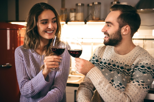 Schönes glückliches junges Paar, das romantischen Abend zusammen zu Hause verbringt, Rotwein trinkt, röstet