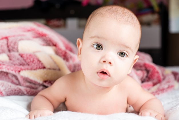 Schönes glückliches kleines Baby, das im Bett liegt