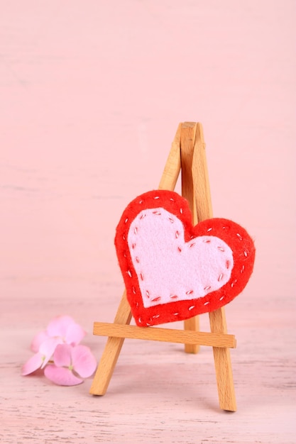 Schönes Herz kleine dekorative Staffelei auf rosa Hintergrund