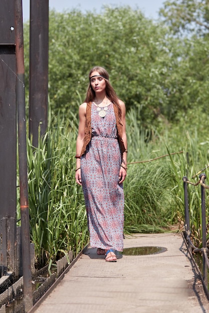 Schönes Hippie-Mädchen, das auf eine Holzbrücke im Park geht