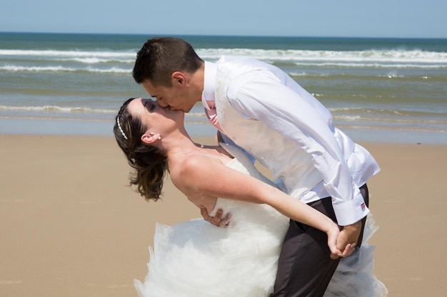 Schönes Hochzeitspaar am Strand mit Hochzeitskleid