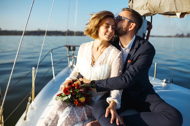 Schönes Hochzeitspaar auf Jacht am Hochzeitstag im Freien im Meer Zusammen Hochzeitstag