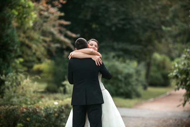 Schönes Hochzeitspaar in den Armen des anderen im Park