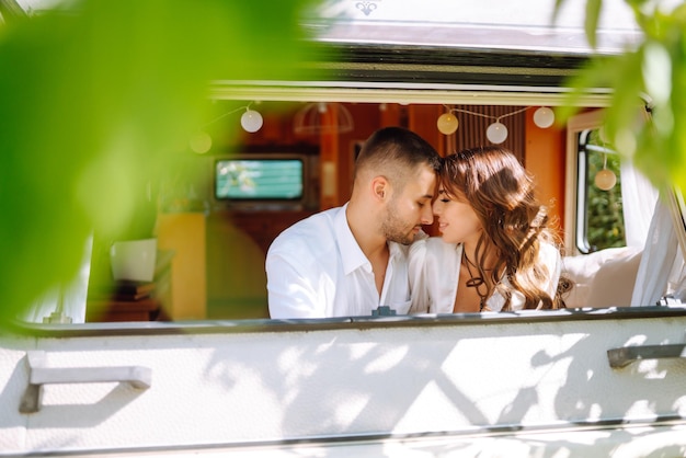 Schönes Hochzeitspaar lacht und küsst sich beim Camping im Wohnmobil in einem romantischen Moment