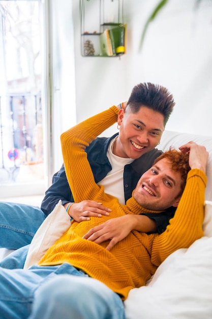 Schönes homosexuelles paar, das zu hause auf dem sofa-porträt romantisch ist und lgbt-konzept kuschelt