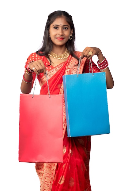 Schönes indisches junges Mädchen, das mit Einkaufstaschen auf einem weißen Hintergrund hält und aufwirft