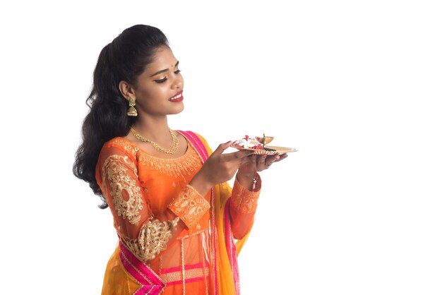 Schönes indisches junges Mädchen, das pooja thali hält oder Anbetung auf Weiß durchführt