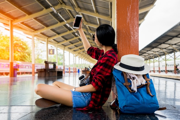 schönes junges asiatisches Mädchen, das alleine an der Bahnstation reist