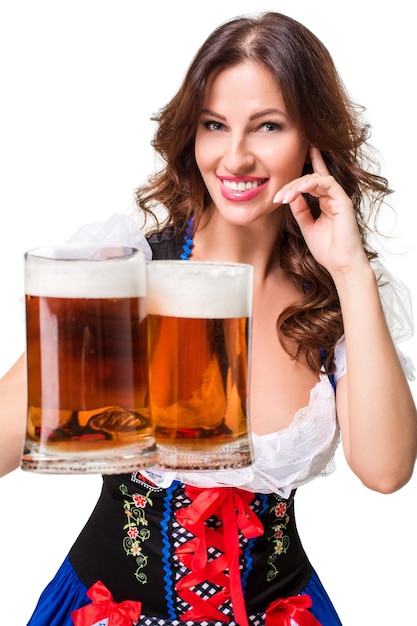 Foto schönes junges brunettemädchen im dirndl trinkt aus oktoberfest-bierkrug heraus. isoliert auf weißem hintergrund.