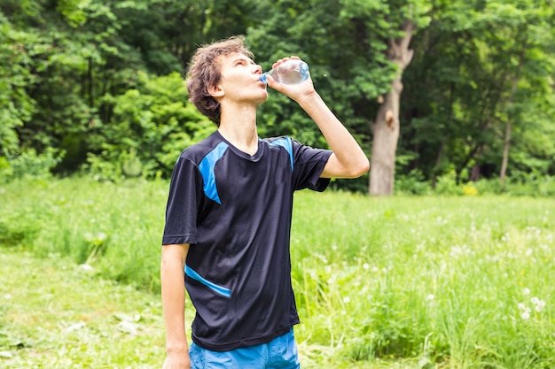 Schönes junges Joggertrinkwasser nach harter Übung im Garten