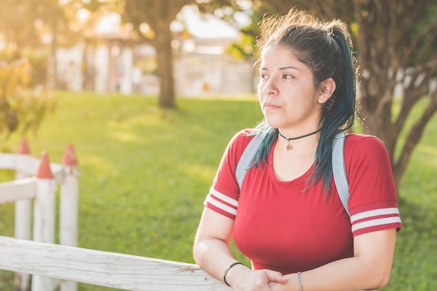 Schönes junges lateinisches College-Mädchen mit schönem Sonnenuntergang im Hintergrund lenkte das Denken ab