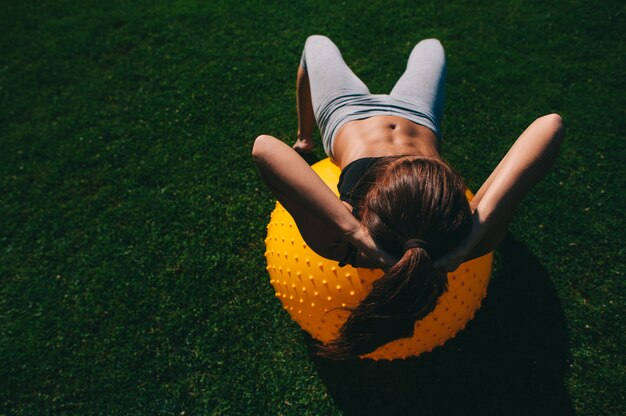 Schönes junges Mädchen, das Übungen mit Sitzball tut