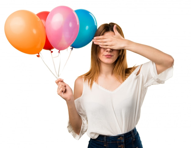 Schönes junges Mädchen, das einen Ballon hält und ihre Augen bedeckt