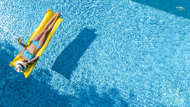 Schönes junges Mädchen, das im Schwimmbad entspannt, Frau schwimmt auf aufblasbarer Matratze und hat Spaß im Wasser im Familienurlaub