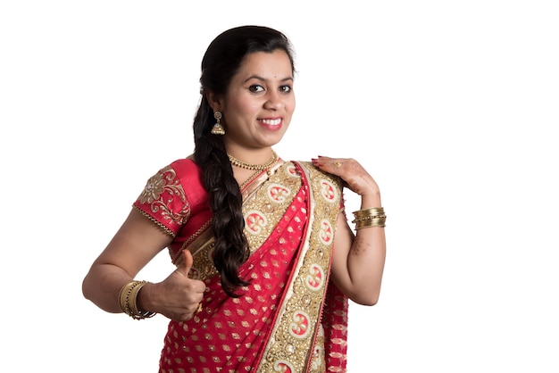Schönes junges Mädchen, das im traditionellen indischen Saree auf Weiß aufwirft