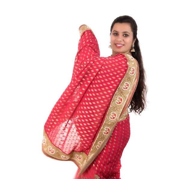 Schönes junges Mädchen, das im traditionellen indischen Saree auf Weiß aufwirft.