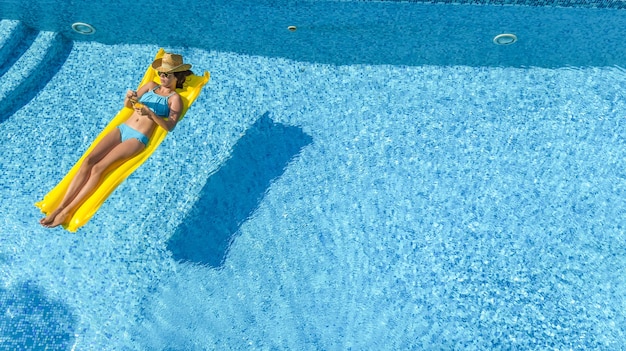 Schönes junges Mädchen, das in Schwimmbadfrau auf aufblasbarer Matratze Luftaufnahme entspannt