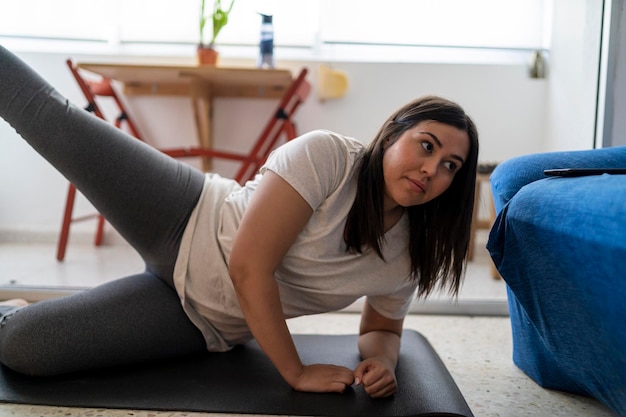 Foto schönes junges mädchen, das mit ihrer schwarzen katze im wohnzimmer ihres hauses sport übt