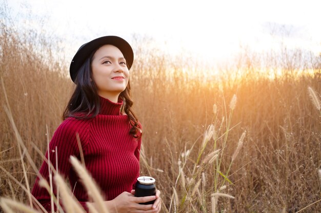 Schönes junges Mädchen hält Kaffee auf der Wiese