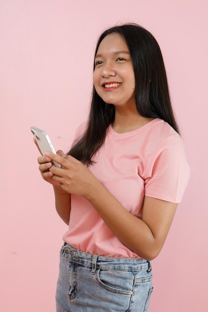 Schönes junges Mädchen hält Smartphone auf rosa Hintergrund