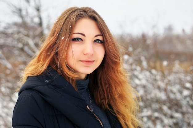 Schönes junges Mädchen im Winter im kalten verschneiten Wald