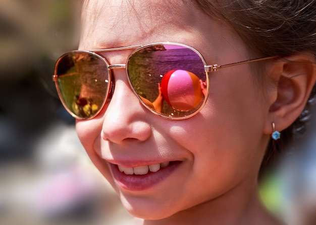 Schönes junges Mädchen in der Sonnenbrille mit Strandballreflexion