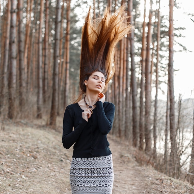 Schönes junges Mädchen in einem schwarzen Kleid, das im Park steht