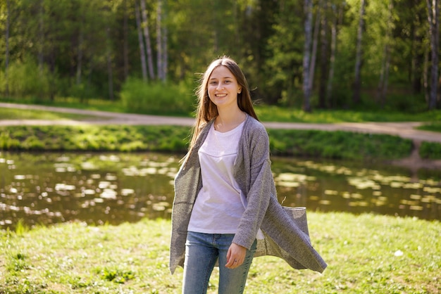 Schönes junges Mädchen in Jeans und einem weißen T-Shirt geht nahe dem See