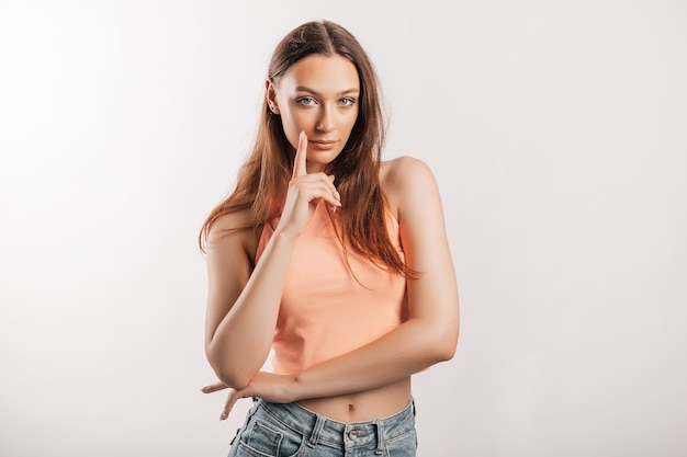 Schönes junges Mädchen lächelt und posiert in die Kamera schaut auf einem weißen isolierten Hintergrund. Positive Brunettefrau. Freundlicher Blick. Schönheitsgesicht.