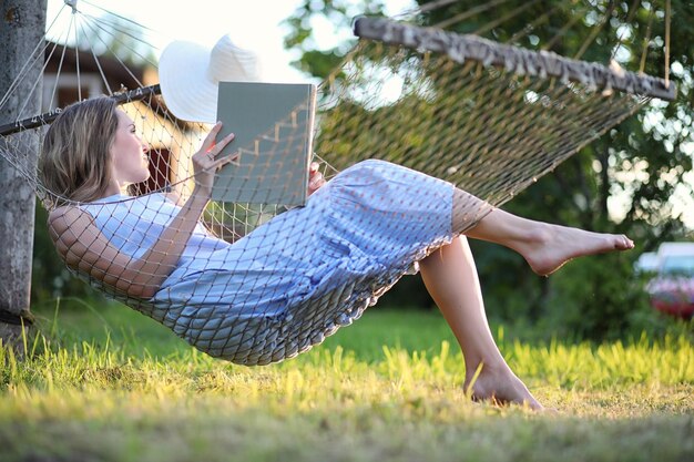 Schönes junges Mädchen liegt und liest im Sommer im Freien ein Buch