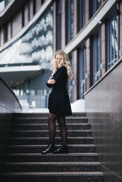 Schönes junges Mädchen mit blonden welligen Haaren auf Treppen