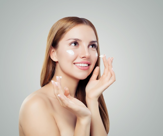 Schönes junges Mädchen mit Creme auf der gesunden Haut Schönheit Gesicht Gesichtsbehandlung Konzept