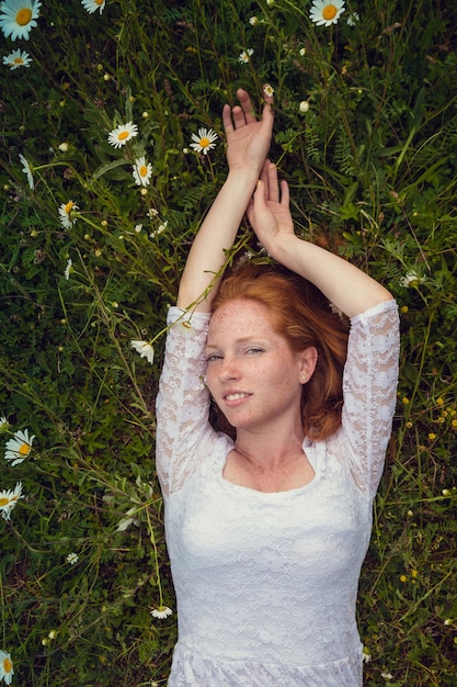 Foto schönes junges mädchen mit den gelockten roten haaren im kamillenfeld