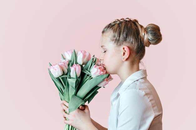 Schönes junges Mädchen mit einem Bündel der rosa Tulpenblumen-Seitenansicht