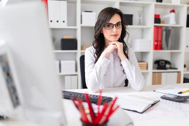 Schönes junges Mädchen sitzt am Tisch im Büro.