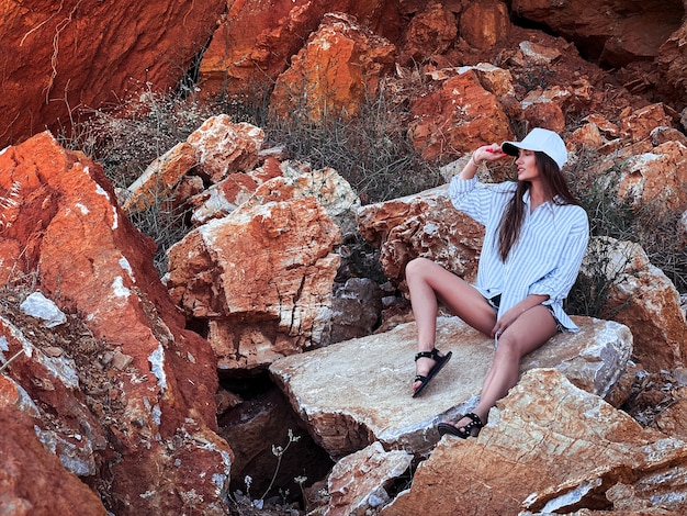 Schönes junges Mädchen sitzt in den Felsen in der Steinschlucht